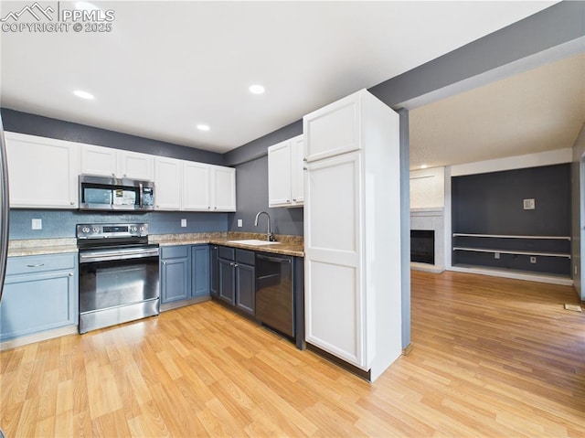 3130 Haystack Dr, Colorado Springs, CO 80922 - kitchen with white cabinets, appliances with stainless steel finishes, a sink, light wood finished floors, and recessed lighting
