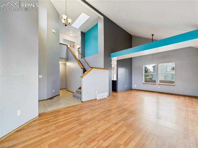 3130 Haystack Dr, Colorado Springs, CO 80922 - unfurnished living room with high vaulted ceiling, wood finished floors, a skylight, visible vents, and stairway