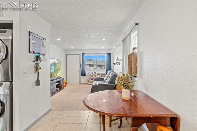 2246 Bison Dr, Colorado Springs, CO 80911 - corridor featuring stacked washer and dryer, a textured wall, light carpet, a textured ceiling, and light tile patterned floors