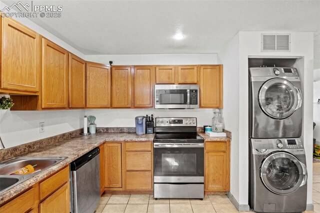 2246 Bison Dr, Colorado Springs, CO 80911 - kitchen featuring visible vents, stacked washer and clothes dryer, light tile patterned floors, and stainless steel appliances