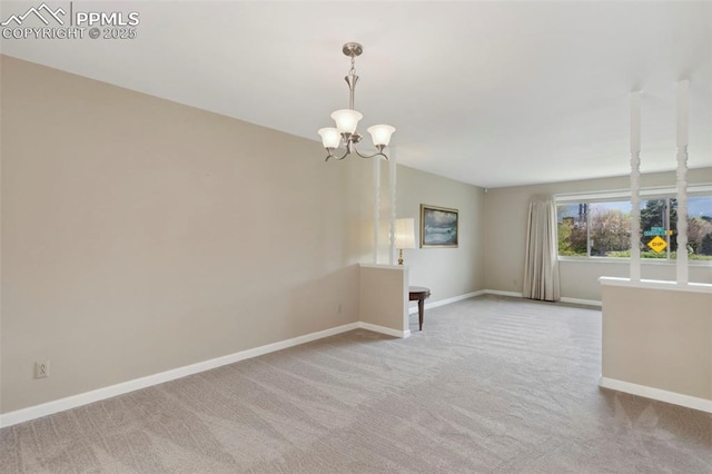 carpeted spare room featuring baseboards and a notable chandelier