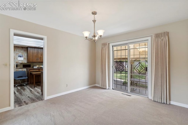 spare room featuring an inviting chandelier, carpet floors, baseboards, and visible vents