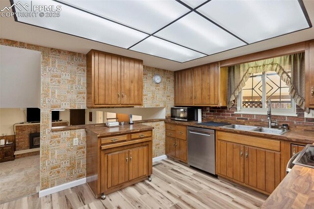 kitchen featuring a sink, appliances with stainless steel finishes, light wood-type flooring, and brown cabinets