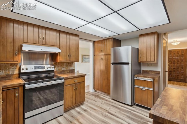 kitchen with decorative backsplash, wooden counters, appliances with stainless steel finishes, under cabinet range hood, and light wood-style flooring
