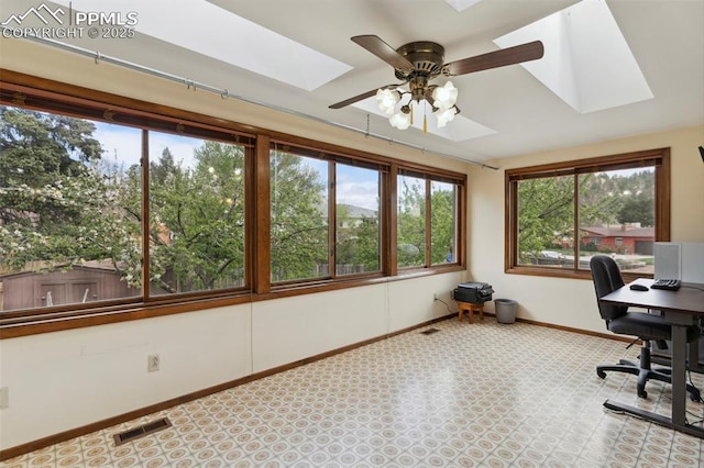 unfurnished office featuring ceiling fan, visible vents, a skylight, baseboards, and carpet flooring