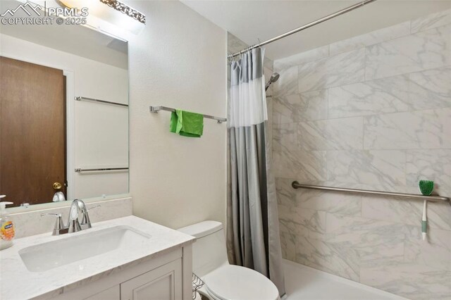 bathroom with vanity, a tile shower, and toilet