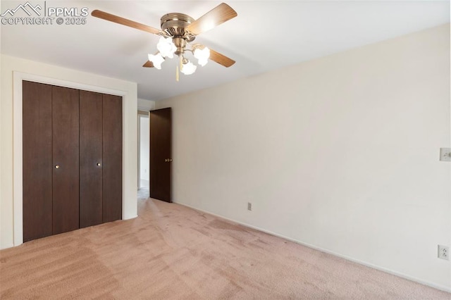 unfurnished bedroom with a ceiling fan, light colored carpet, and a closet