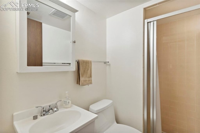 bathroom featuring toilet, visible vents, a shower stall, and vanity