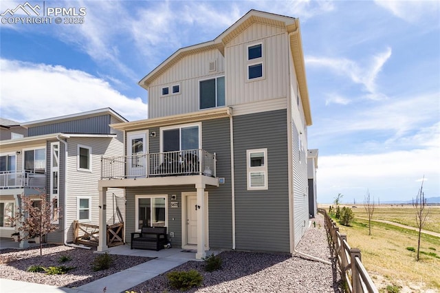 view of front of home with a balcony, fence, a patio, and board and batten siding