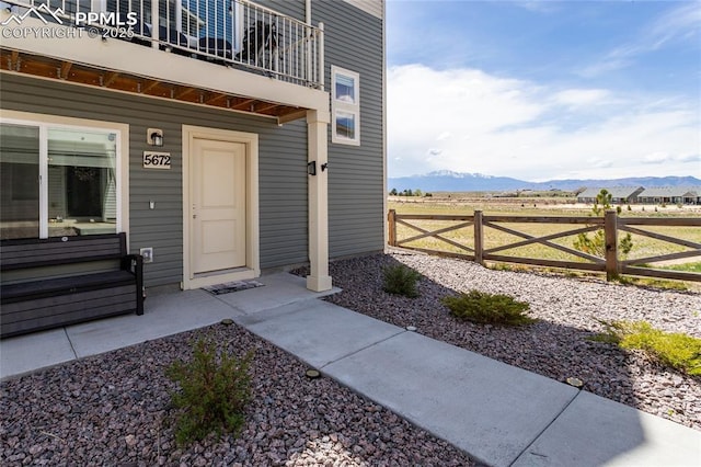 view of exterior entry with a mountain view and fence