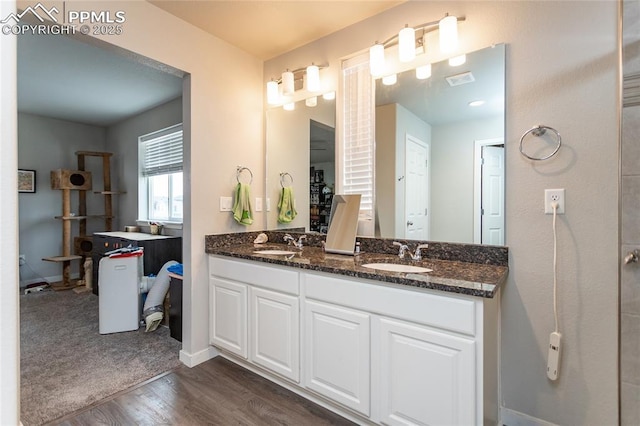 bathroom featuring visible vents, double vanity, a sink, and wood finished floors