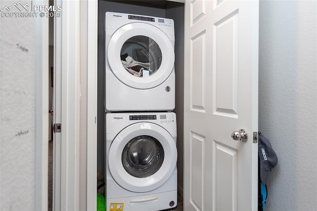 clothes washing area with stacked washing maching and dryer and laundry area