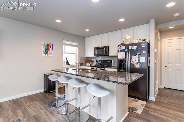 kitchen with a sink, stainless steel appliances, baseboards, and wood finished floors