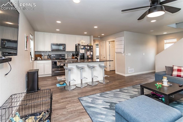 living room featuring dark wood-type flooring, baseboards, visible vents, ceiling fan, and recessed lighting