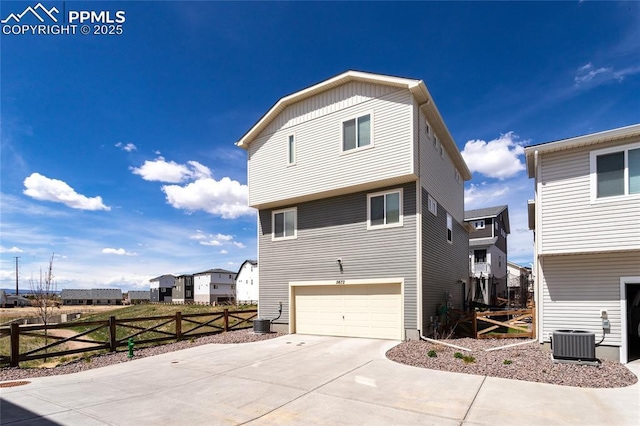 view of side of property featuring concrete driveway, fence, an attached garage, and central AC