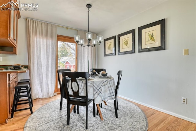 dining area with baseboards, light wood finished floors, and a notable chandelier
