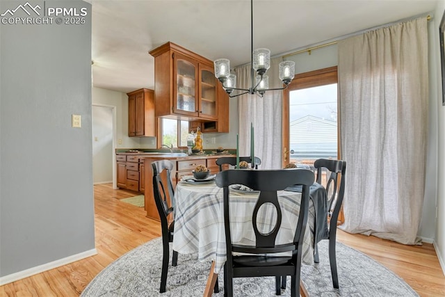 dining area with baseboards, a chandelier, and light wood finished floors
