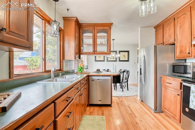 kitchen featuring a chandelier, a sink, light wood-style flooring, hanging light fixtures, and stainless steel appliances