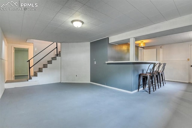 bar with baseboards, stairs, concrete flooring, and bar area