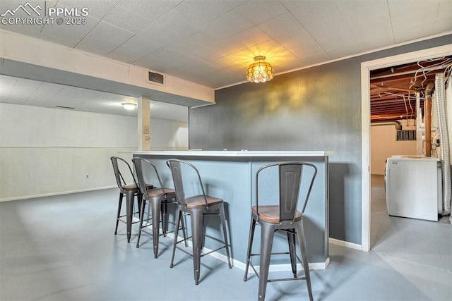 bar featuring washer / dryer, baseboards, concrete flooring, and visible vents
