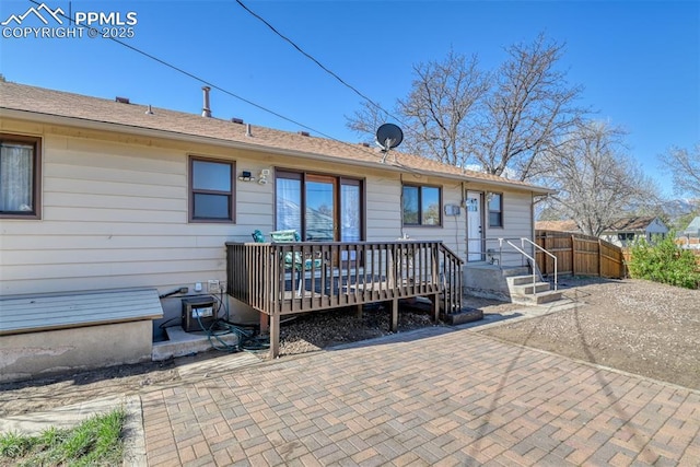 rear view of property with fence and a wooden deck