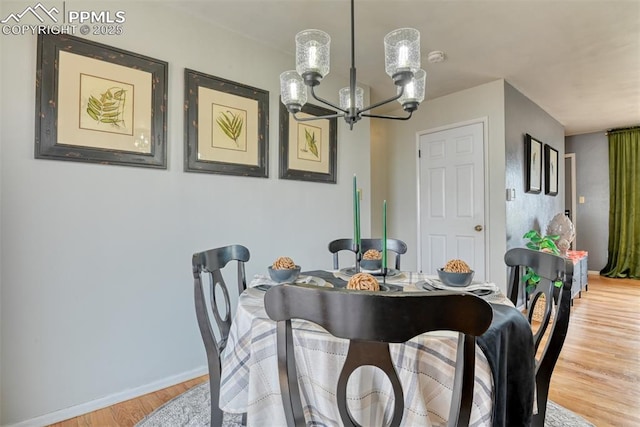 dining space with baseboards, wood finished floors, and a chandelier