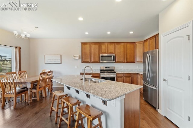 kitchen featuring brown cabinetry, a sink, wood finished floors, and stainless steel appliances