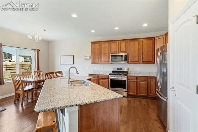 kitchen featuring appliances with stainless steel finishes, brown cabinets, a sink, dark wood-style floors, and recessed lighting