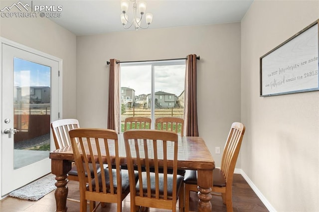 dining space featuring baseboards, wood finished floors, and a chandelier