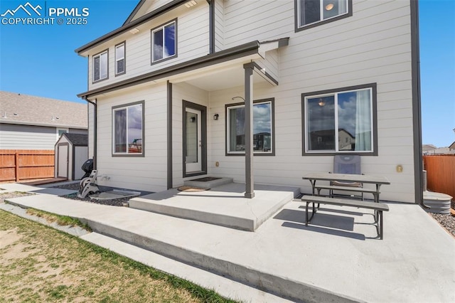 back of property featuring a storage shed, a patio, fence, and an outdoor structure