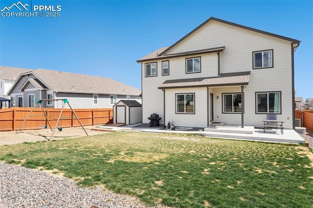 rear view of house with a fenced backyard, a storage unit, and a patio