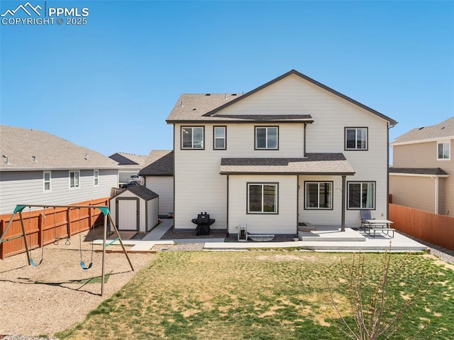 back of house featuring a storage unit, a fenced backyard, a patio area, an outdoor structure, and a yard