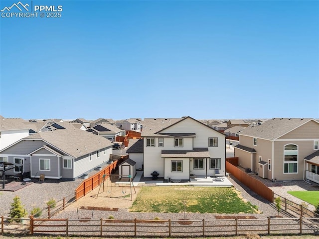 rear view of property featuring a residential view, a fenced backyard, a yard, and a patio area