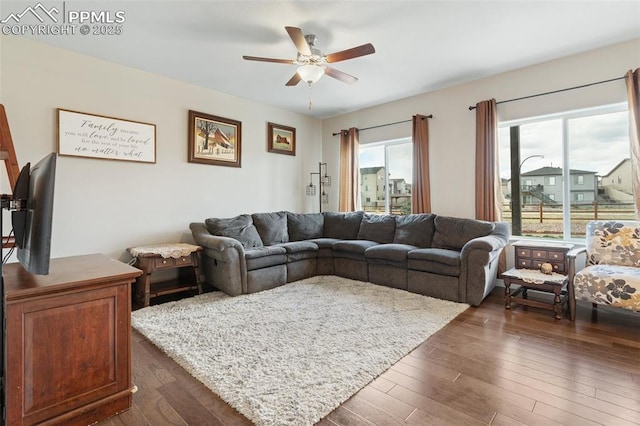 living area with ceiling fan, dark wood-style floors, and a healthy amount of sunlight