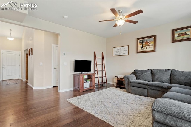 living area featuring dark wood-style flooring, ceiling fan, and baseboards