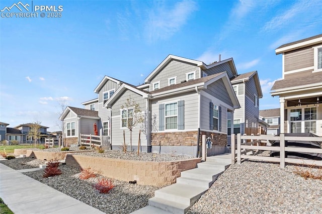 view of front facade with a residential view, fence, and stone siding