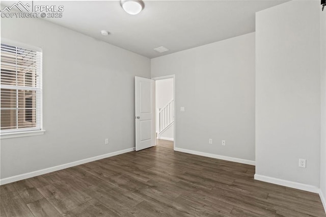 spare room featuring dark wood-style flooring and baseboards
