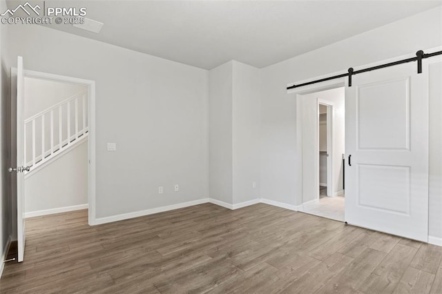 interior space with baseboards, a spacious closet, a barn door, and wood finished floors