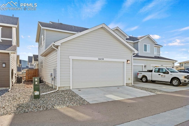 view of side of home with concrete driveway, an attached garage, fence, and central AC unit