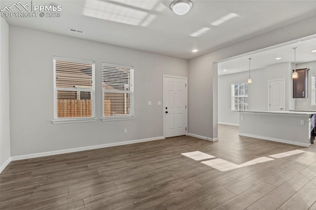 unfurnished living room featuring dark wood-style flooring, baseboards, and visible vents