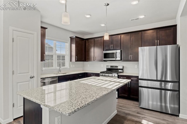 kitchen featuring dark brown cabinetry, visible vents, wood finished floors, a sink, and stainless steel appliances