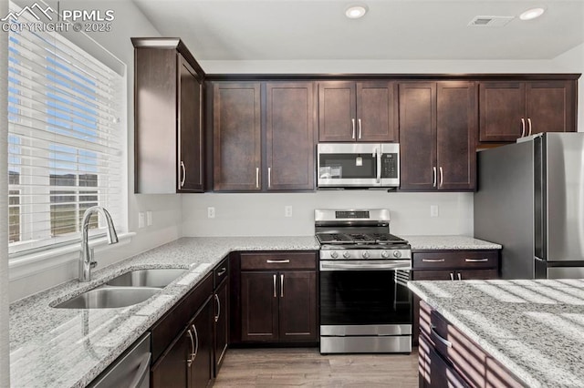 kitchen featuring light stone countertops, appliances with stainless steel finishes, a wealth of natural light, and a sink