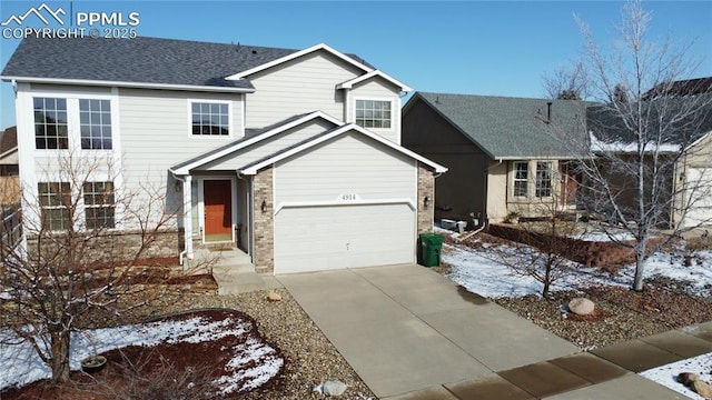 traditional-style house featuring a garage, a shingled roof, and concrete driveway