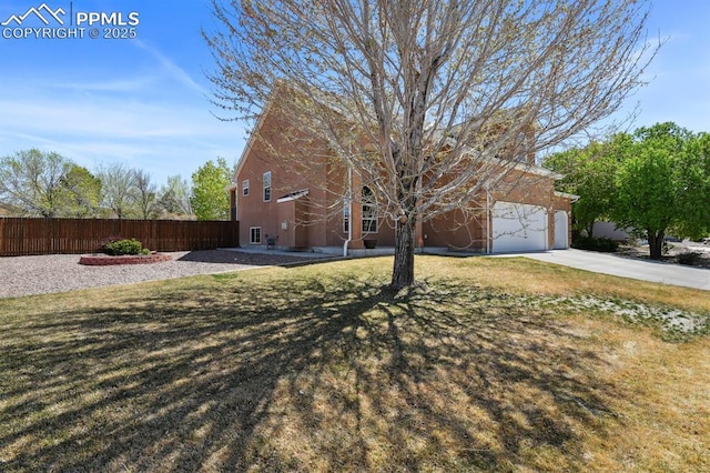 view of front of property featuring an attached garage, fence, driveway, and a front yard