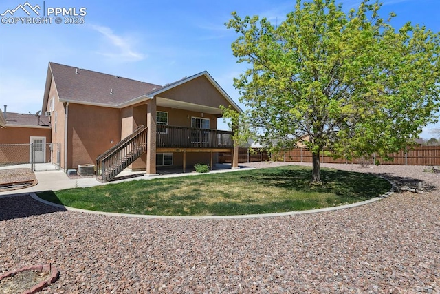 rear view of house with stairs, stucco siding, a fenced backyard, a gate, and a yard