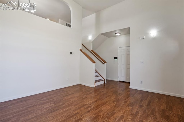 unfurnished living room featuring baseboards, stairs, wood finished floors, and visible vents
