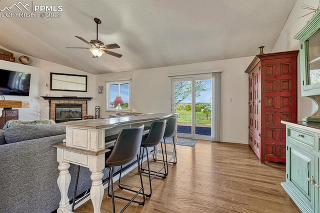 16440 Eastonville Rd, Elbert, CO 80106 - kitchen with vaulted ceiling, ceiling fan, a tile fireplace, light wood-style flooring, and open floor plan