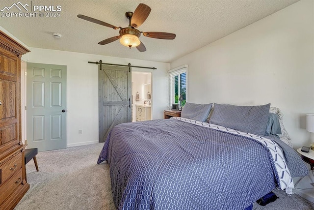 16440 Eastonville Rd, Elbert, CO 80106 - bedroom with carpet floors, a barn door, ceiling fan, a textured ceiling, and connected bathroom