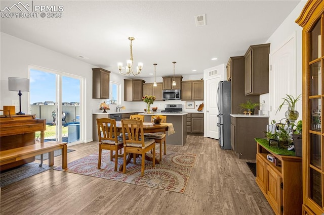 dining area with a chandelier, wood finished floors, visible vents, and recessed lighting