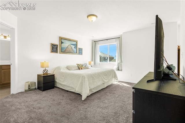 carpeted bedroom with ensuite bath and baseboards
